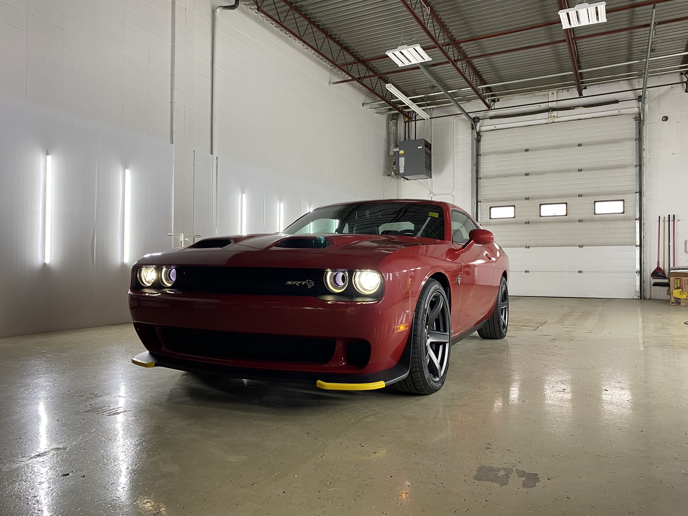 A Dodge Challenger Hellcat finished in gloss red metallic wrap, photographed head on in a Choice Graphics shop bay
