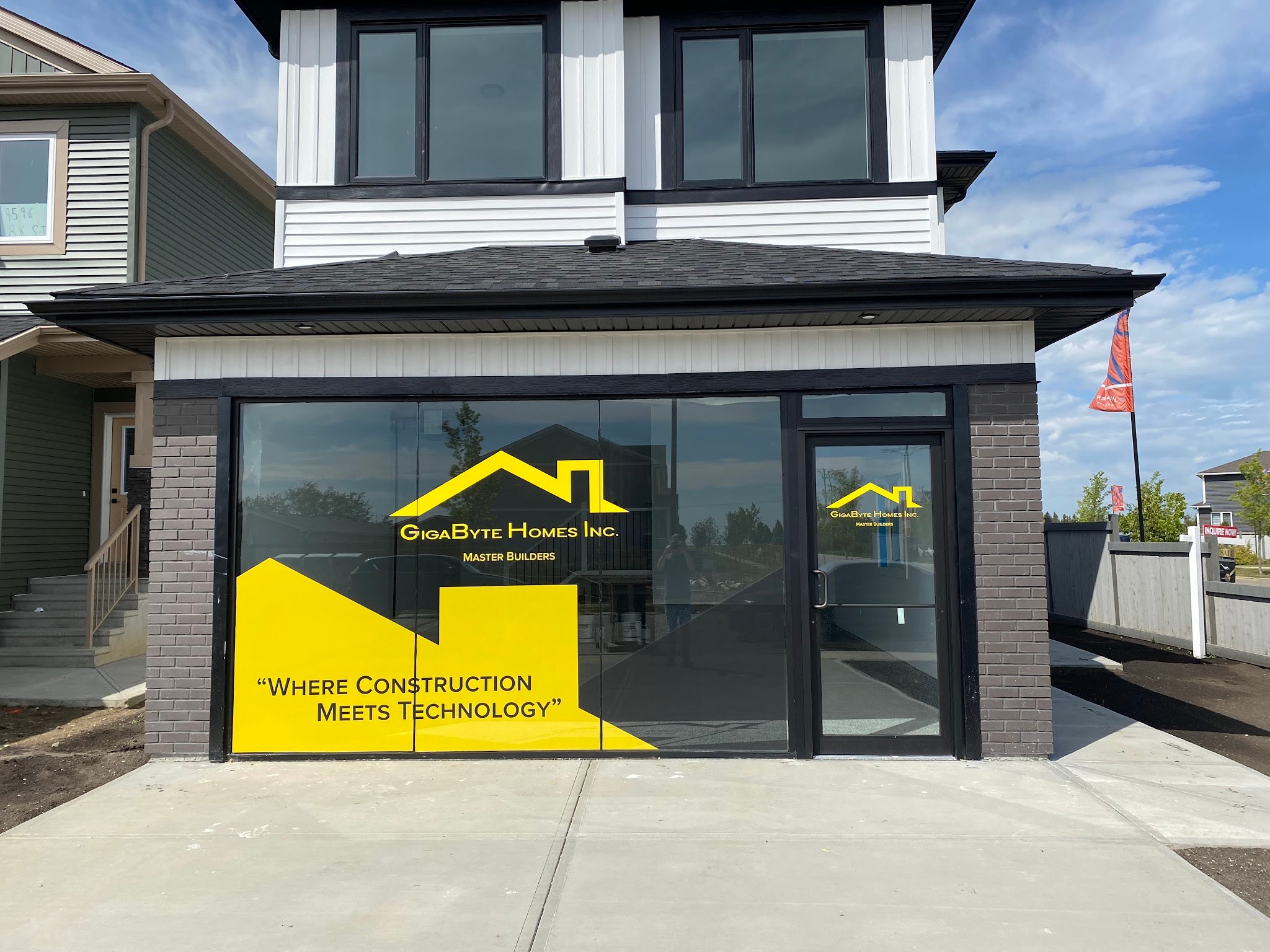 Finished storefront window graphics on a show home sales office, yellow logo panels and lettering applied to the full height glass