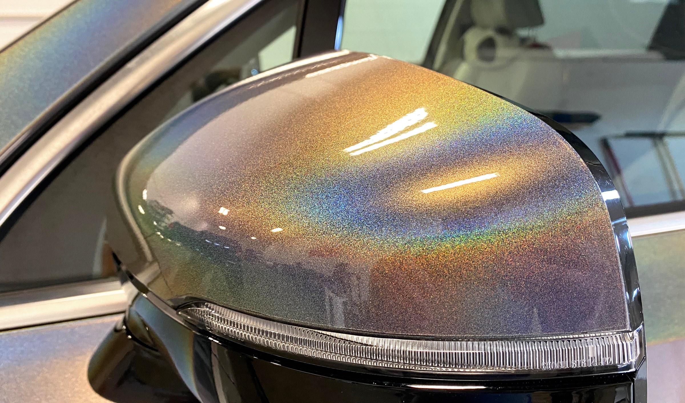 Close up of a wing mirror wrapped in a metallic flake film, showing the flake and the rainbow flip across the curve
